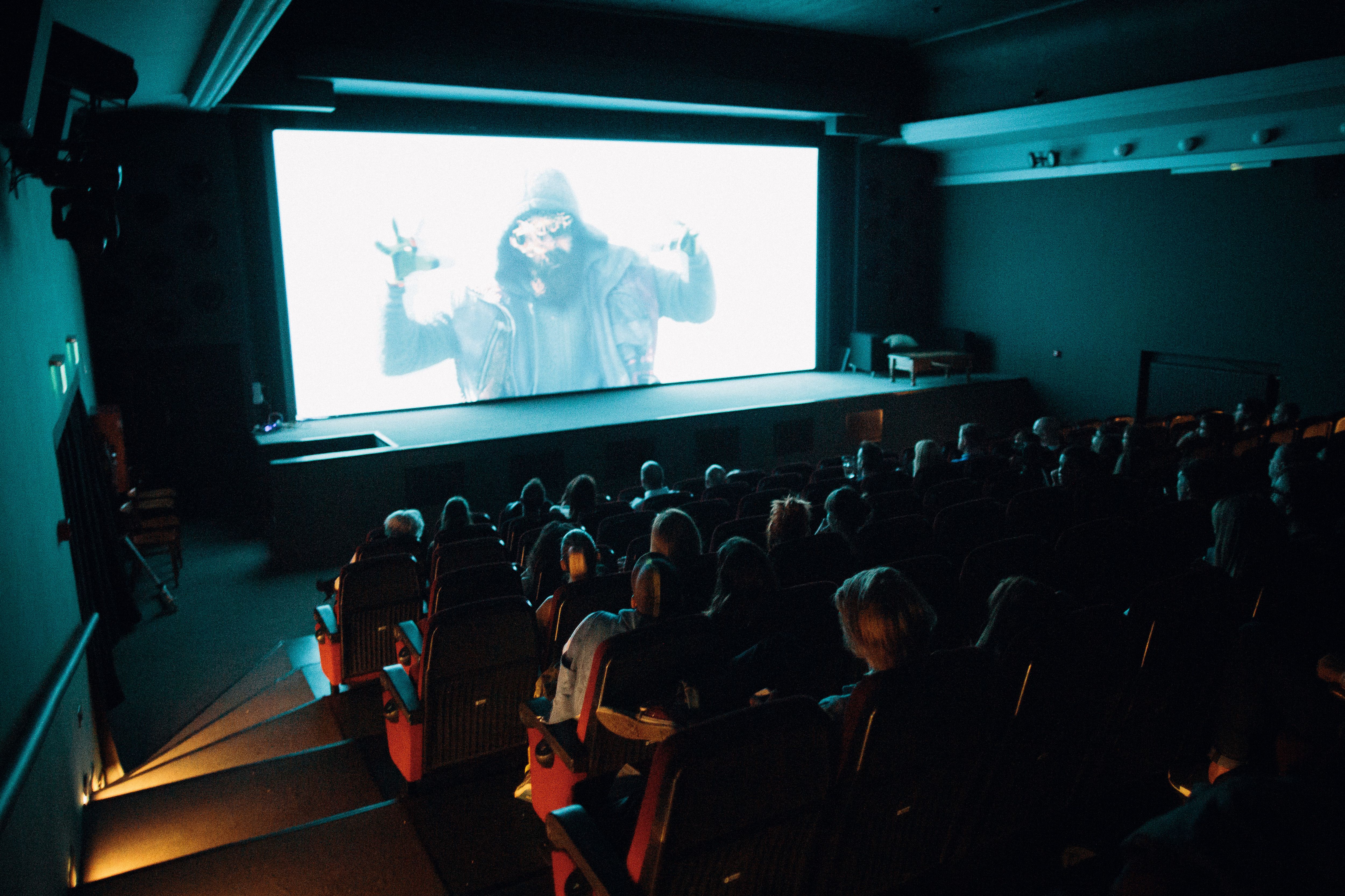 Audience watching a film in a crowded cinema, evoking the shared experience that inspires fan appreciation.