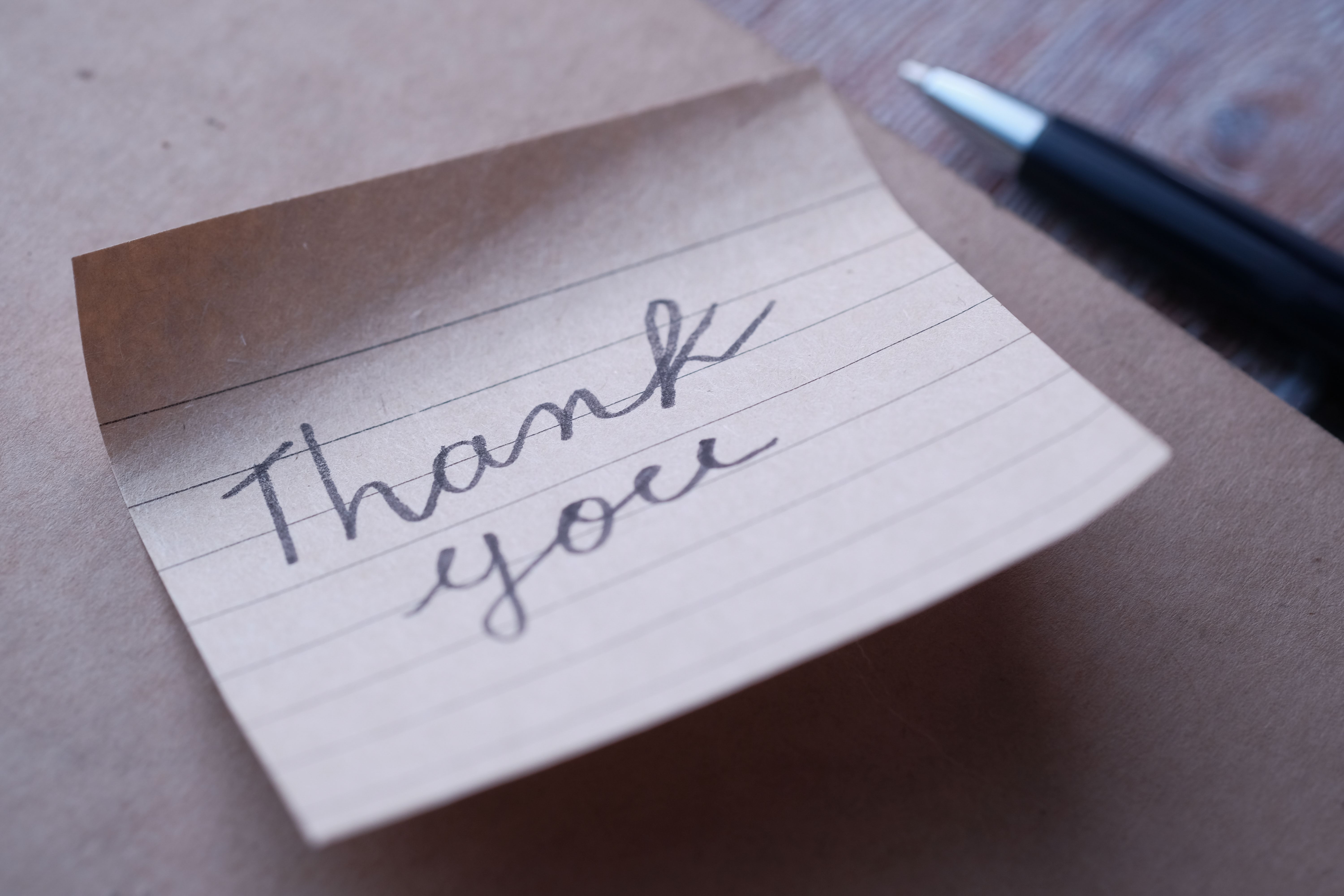 Handwritten thank-you note on brown paper with a pen nearby, illustrating a personal message to a favorite star.
