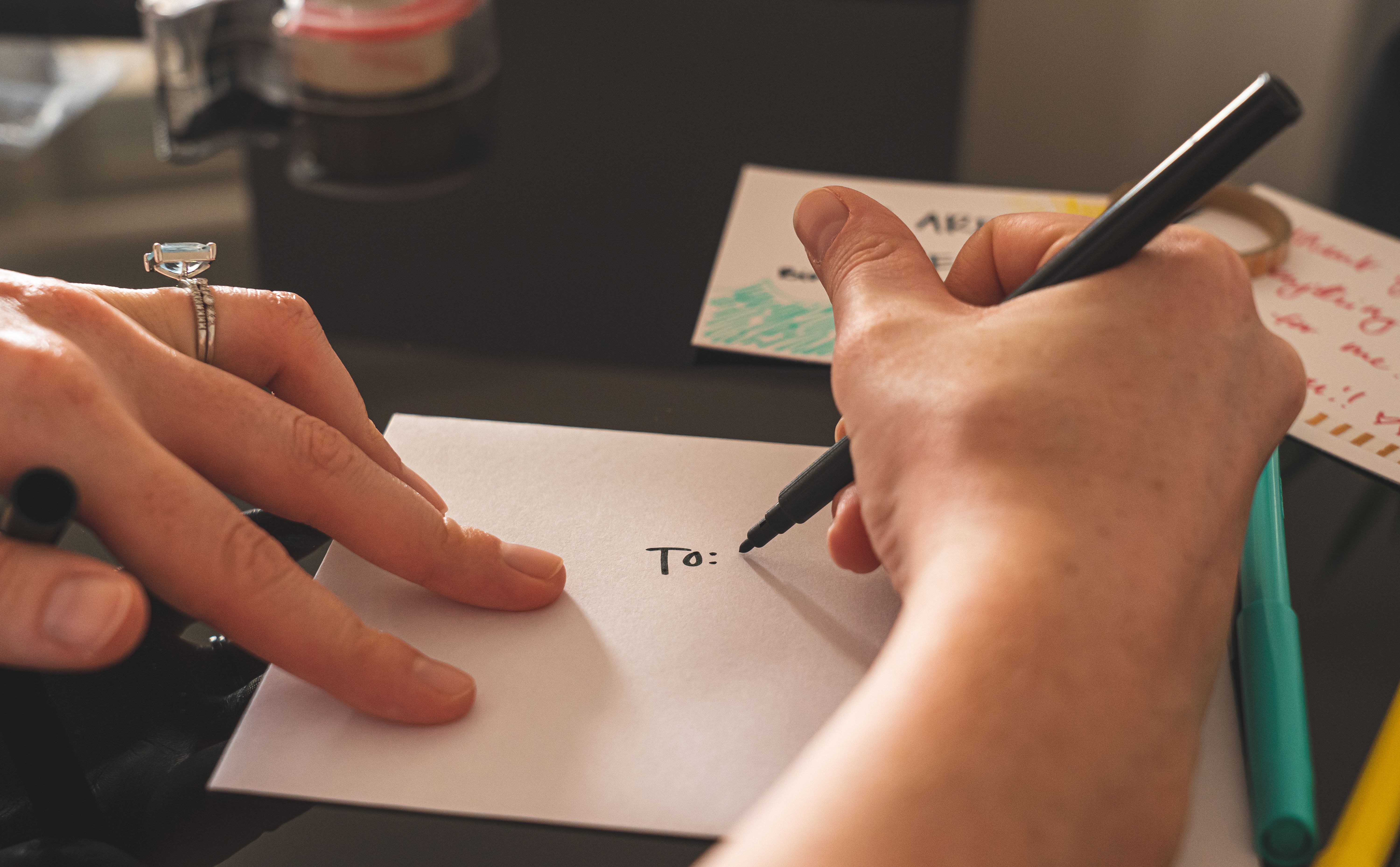Hands writing an address on an envelope, showing the process of preparing a fan letter for mailing.